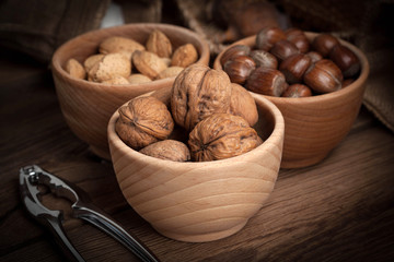 Walnuts, hazelnuts and almonds in-shell in wooden bowl.