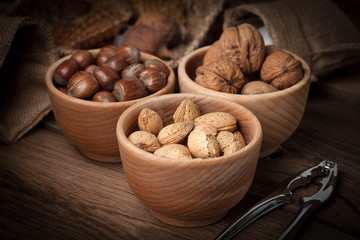 Walnuts, hazelnuts and almonds in-shell in wooden bowl.