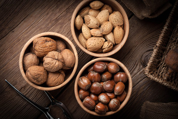 Walnuts, hazelnuts and almonds in-shell in wooden bowl.