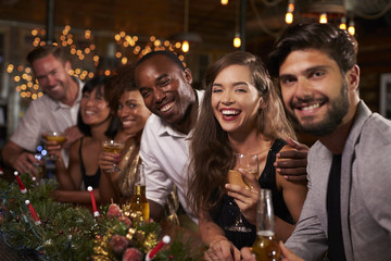 Friends enjoying Christmas celebrations look to camera