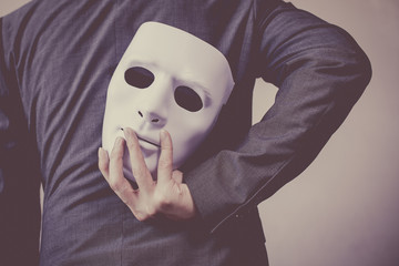 Business man carrying white mask to his body indicating Business fraud and faking business...