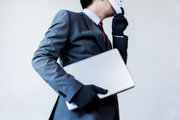 Business man in white mask wearing gloves and stealing computer and digital information - fraud, hacker, theft, cyber crime concept
