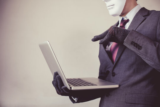 Business Man In White Mask Wearing Gloves And Using Computer - Fraud, Hacker, Theft, Cyber Crime Concept