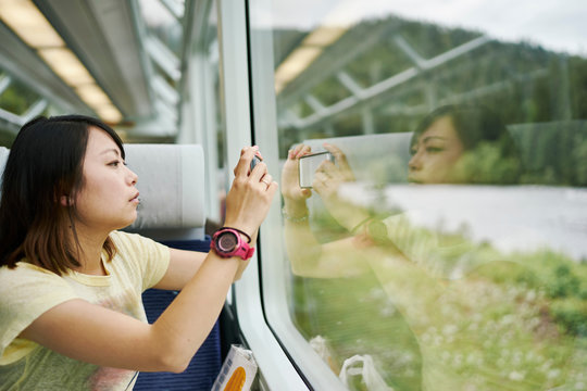 Female tourist photographing through passenger train window, Chur, Switzerland