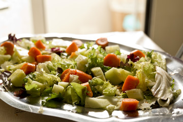 Salad varied on a metal tray. Shooting horizontal to taking advantage of the natural light coming through a window.