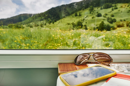 Sunglasses and smartphone by passenger train window, Chur, Switzerland