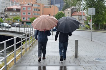 two men on the street with umbrellas in the rain