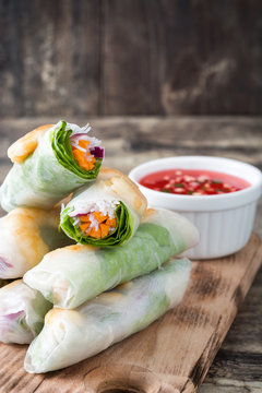 Vietnamese rolls with vegetables, rice noodles and prawns on wooden background
