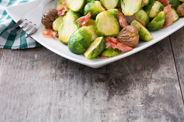 Brussels sprouts with chestnuts and bacon on wooden table
