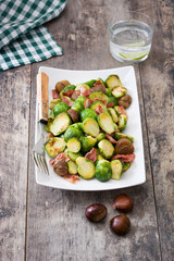 Brussels sprouts with chestnuts and bacon on wooden table
