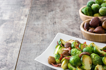 Brussels sprouts with chestnuts and bacon on wooden table
