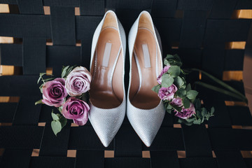 Bridal shoes stand next to pink flowers