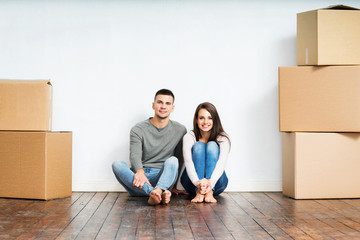 Couple sitting on the floor next to cardboard boxes
