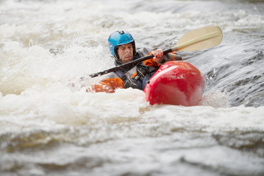 Imbalanced male kayaker paddling River Dee rapids