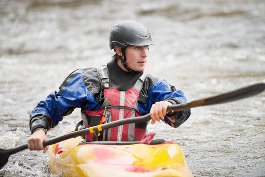 Young male kayaker paddling River Dee rapids