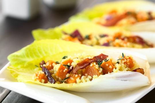 Chicoree Bl&auml;tter belegt mit einem Salat aus Couscous, K&uuml;rbis, Speck, rote Zwiebel und Thymian, fotografiert mit nat&uuml;rlichem Licht (Selektiver Fokus, Fokus ein Drittel in das Bild)