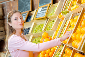 Lady choosing oranges from crates