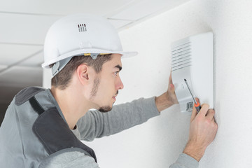 Man fitting alarm to wall