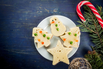 Funny Christmas breakfast, sandwiches in the form of Christmas trees, reindeer and snowmen. With branches of Christmas trees and decorations, top view