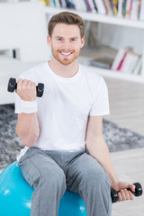attractive young man with swiss ball doing exercises at home