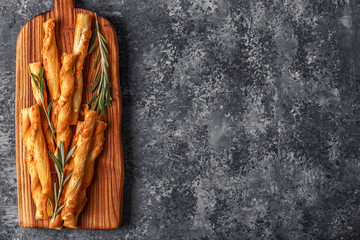 Grissini bread sticks on wooden cutting board  over concrete tex