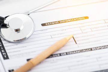Stethoscope on patient form and pen on the desk.