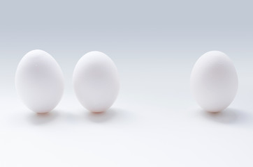 A photo of three white eggs on the grey background.