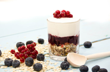 Yogurt with granola and fresh blueberries, in glass bowl over old wood background. Vintage effect.