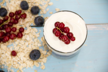 Yogurt with granola and fresh blueberries, in glass bowl over old wood background. Vintage effect.