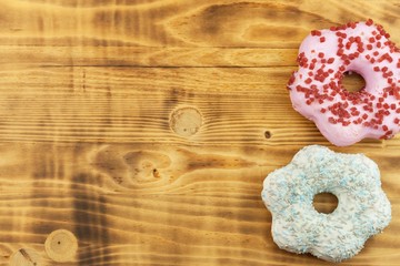 Donuts on wooden background. Sweet donuts with sugar icing. Unhealthy food. The dangers of obesity.
