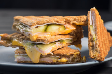 Pile of grilled sandwiches with cheese and ham.