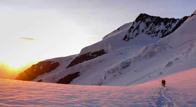 a mountain guide and client on a glacier at sunrise in the Swiss Alps heading towards Bellavista peak