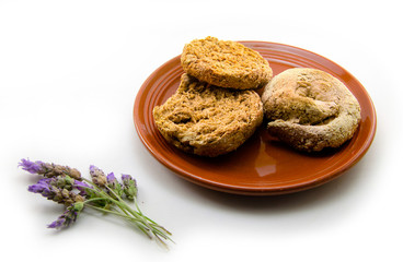 A ceramic plate with ntako isolated on white background and a bunch of lavender flowers. Ntakos is a Cretan traditional food like dried bread from barley and wheat.
