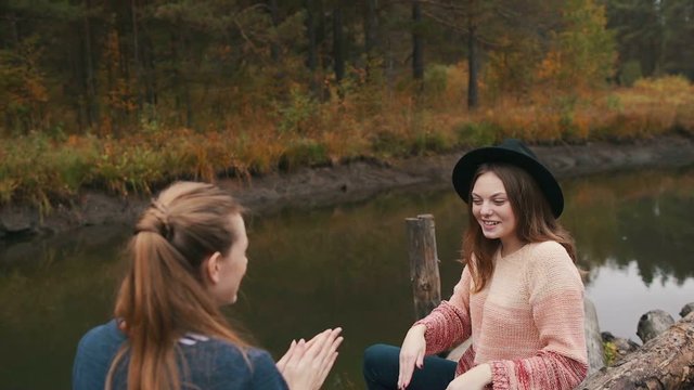 Two friends play hand-clapping game. On the logs. Autumn forest