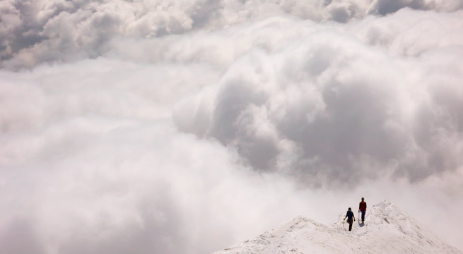 a mountain guide and client on an exposed ridge in the Swiss Alps before an oncoming storm