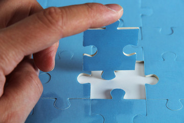 Hand hält fehlendes Puzzleteil mit blauem Puzzle
