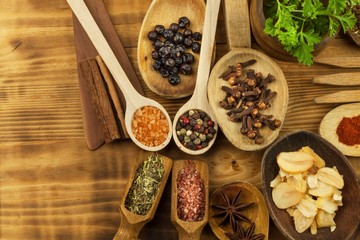 Various kinds of spices on the kitchen table. Seasoning food. Sales of exotic spices. Advertising on spices. Powder spices on spoons in wooden table background.
