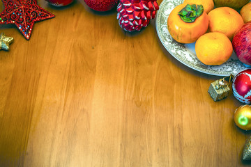 Christmas background with decorations and fruits on a plate on wooden table.