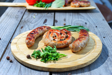 Grilled sausages served on wooden plate over wooden table.  Selective focus.