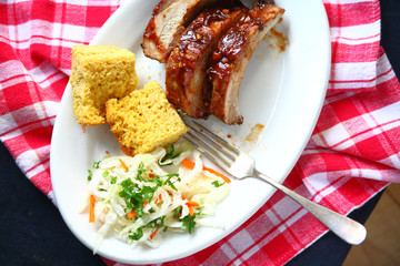 Overhead view of garlic-barbecue sauce-glazed pork baby back ribs with cornbread and coleslaw