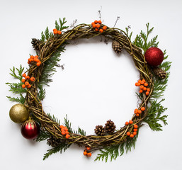 Christmas wreath of vines with decorative ornaments, thuja branches, rowanberries and cones. Flat lay, top view