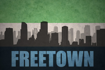 abstract silhouette of the city with text Freetown at the vintage sierra leone flag