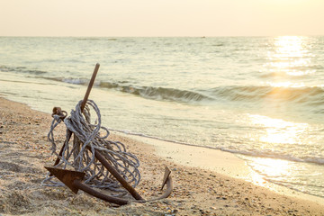 RUSTY ANCHOR WET BEACH SAND AND WHITE SEA-WAVE FOAM