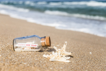 message in a bottle and starfish/bottle with a message happy new year on sandy beach in Florida.