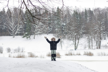 Happy inspired boy rises hands  in snow nature landscape. Man wh