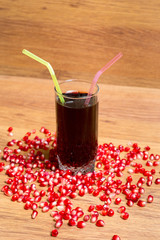 A glass of delicious pomegranate juice, pomegranate and pomegranate seeds on a table