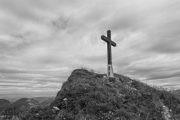 Black and white image of a cross on hillside in the Swiss alps