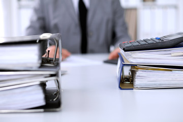 Binders with papers are waiting to be processed with business woman back in blur. Accounting planning budget, audit and  insurance concept