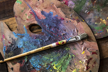 Used Artist paint brush and palette of colorful oil paint on wooden background   for drawing and painting