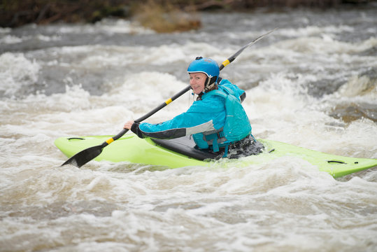 Young female kayaker paddling River Dee rapids